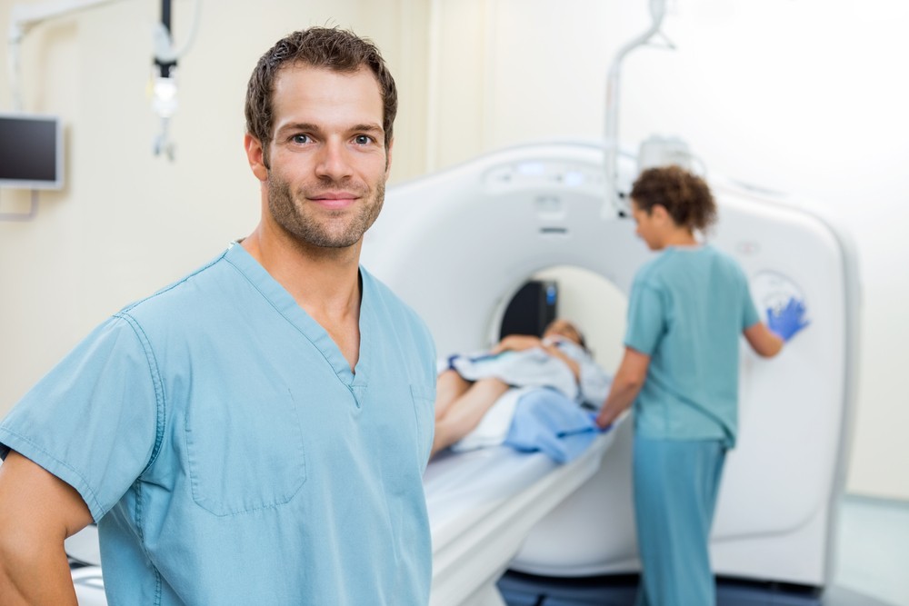 Portrait of young male nurse with colleague preparing patient for CT scan|mednax consolidation company stock market